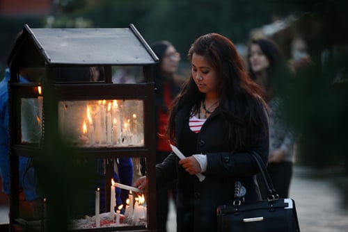A woman lights a candle on Christmas day at Assumption Church in Lalitpur on Thursday.