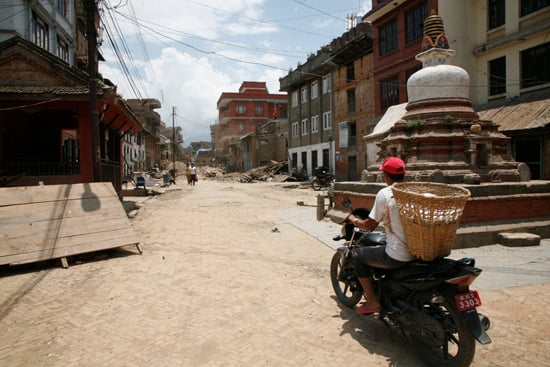 A man carrying a doko rides a bike as he shifts his belongings at Khokana.