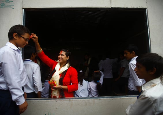 A teacher puts tika on her student's forehead on the occasion of Guru Purnima at Darbar High School on Friday.