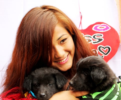A participant poses with rescued puppies during Animal Nepal's Valentine's Day programme.