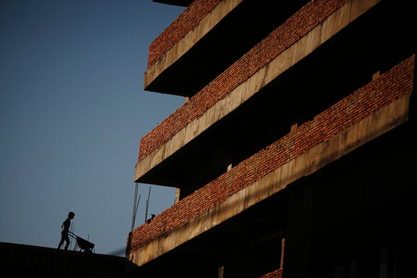 A brick layer pushes a wheelbarrow at a construction site in Maharajganj on Tuesday.