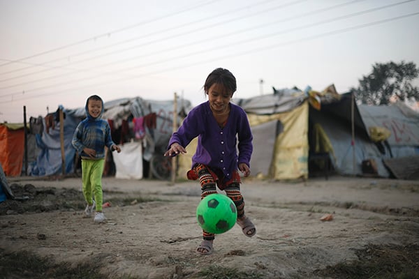 Maya Tamang, 10, plays football with her younger brother outside their makeshift tent in Chuchepati, Kathmandu on Friday. After the earthquake destroyed her house in Sindhupalchok seven months ago, her family has been living here. As the political stand-off over the reconstruction bill continues, the earthquake-displaced children like her have not been able to return to their villages.