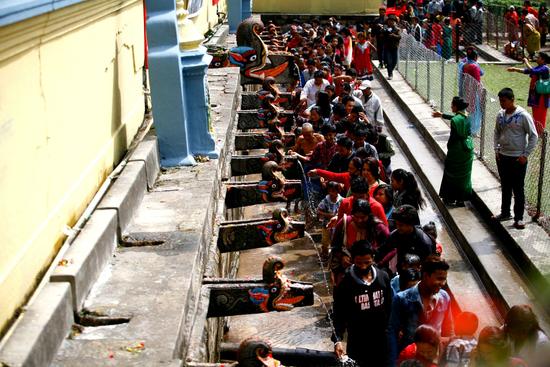 Devotees wash their hands with water at the Balaju Baise Dhara during the Baishakh Asnan festival in Kathmandu on Saturday.