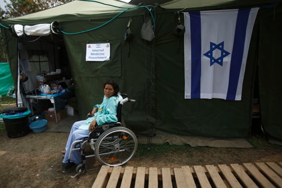 An earthquake victim sits on the wheel chair outside the makeshift clinic of Israel Health Camp in the open field of Chhauni Hospital on Friday.