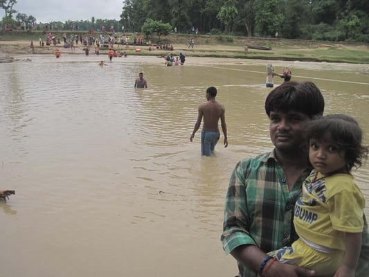 Kaushal Balmiki carries his daughter after crossing the Paruwa Sota river. Last week's flood caused a bridge on the East-West highway to collapse.