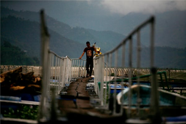 50-year-old Jeevan Dhakal (front) and 37-year-old Bhojraj Timilsina (back) from the Agriculture Research Fishing Centre return back after repairing a drum beneath their fish farm at Fewa Lake in Pokhara on Tuesday.