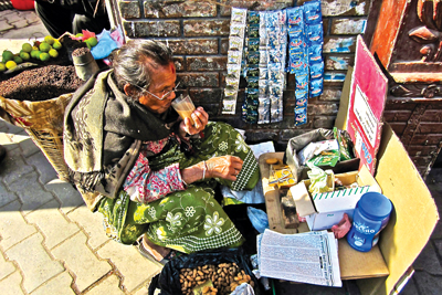 TEA TIME: An elderly woman enjoys break from work with a cup of tea in Kathmandu Durbar square.