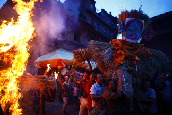 People carry an effigy of the demon Ghantakarna, while another effigy of the demon is burnt, to symbolize the destruction of evil during the Ghantakarna festival in Bhaktapur on Wednesday.