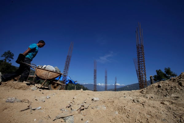 A mason pushes a wheelbarrow full of stones at a construction site of a school damaged in last year's earthquake in Giranchaur, Sindhupalchok on Monday.