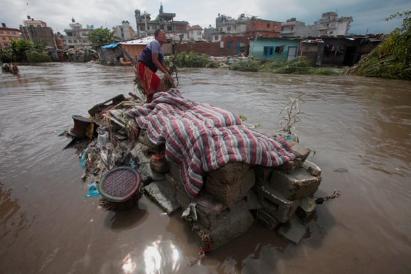 60 year old Shanti Lama collects her belongings after heavy rain on Sunday night caused the Bagmati River to overflow, submerging the squatter-settlement at Shantinagar.