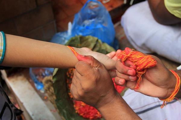'Janai' being tied to a child's hand on Janai Purnima at Baneshwor on Sunday.
