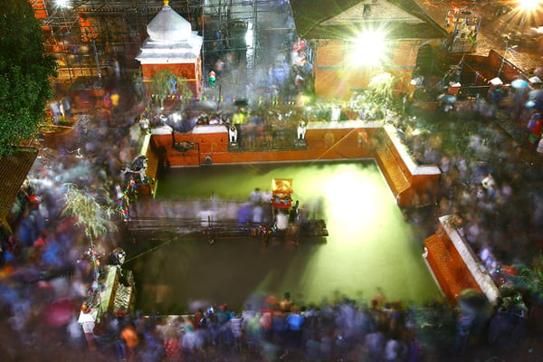 People gather around the Kumbheswor pond to watch the installation of the idol of Lord Shiva in Patan on Sunday. This marks the beginning of the Kumbheshwor mela.