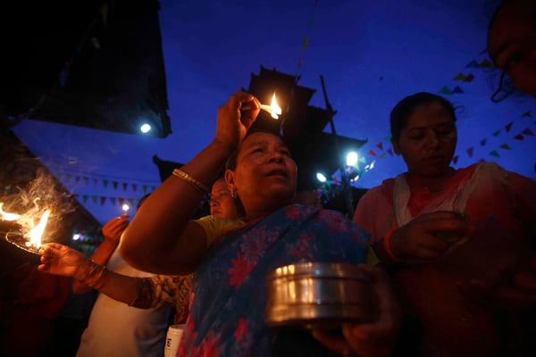 A woman lights a butter lamp on the occasion of Janai Purnima at Kumbeshwor temple in Lalitpur on Sunday.
