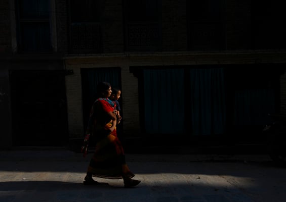 A mother carries her child through Brahma Tole on Wednesday.