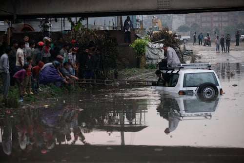 Bystanders help people out of a submerged car below the Balkhu bridge on Thursday.
