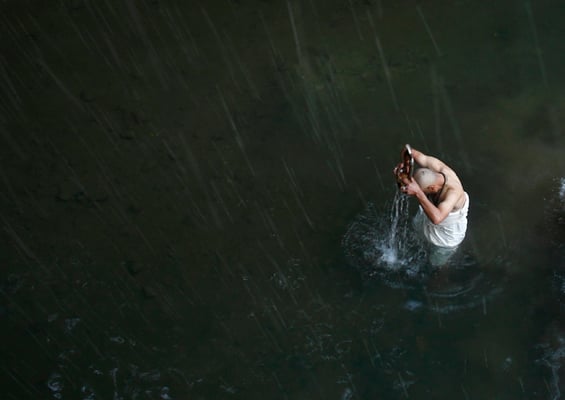 A priest holds the idol of Madhav Narayan as he takes a dip in the Saalinadi river in Sankhu during the Swasthani Brata Katha festival on Thursday.