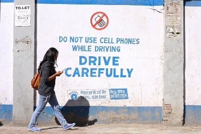 SWITCHED OFF: A woman walks past a sign painted on a wall along Kamaladi on Wednesday.
