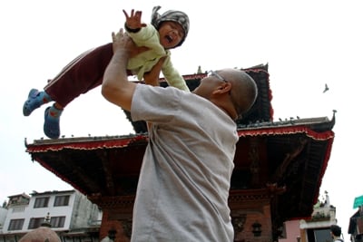 UP IN THE SKY: A father amuses his child by throwing him into the air at Patan Durbar Square on Tuesday.
