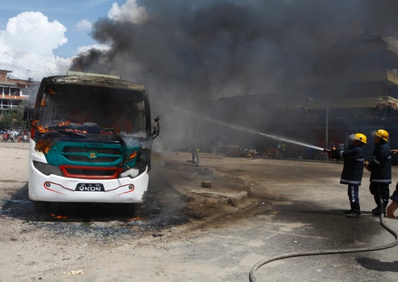 Firefighters try to extinguish a burning bus at Old Bus Park on Sunday. Protesters of opposition parties have carried out demonstrations throughout the valley to oppose the new constitution.