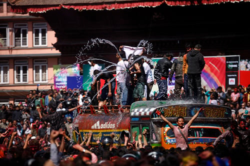A man sprays water at a crowd of people celebrating Holi in Basantapur today.