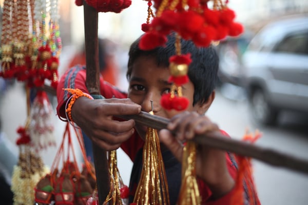 A child sells Tihar decorations by the main road near Bishal Bazaar on Monday.