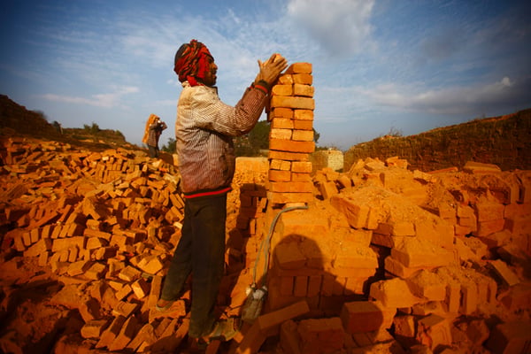 47 year old Dambar Bika of Salyan stacks bricks at a brick factory in Thaiba on Tuesday. He comes to Kathmandu every year to work in the factory.
