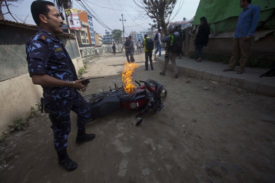 A policeman stands over a burning bike vandalised by UCPN(Maoist) cadres during the first day of the three-day Nepal Bandh on Tuesday.