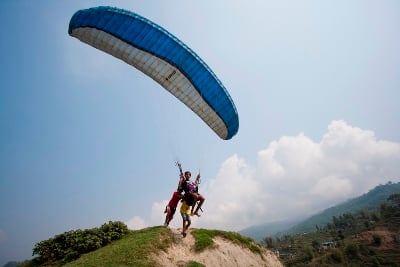 MASTER OF THE AIR: Boys help to push their brother off an elevated ground as he practises controlling a parachute in Pokhara on Friday morning.