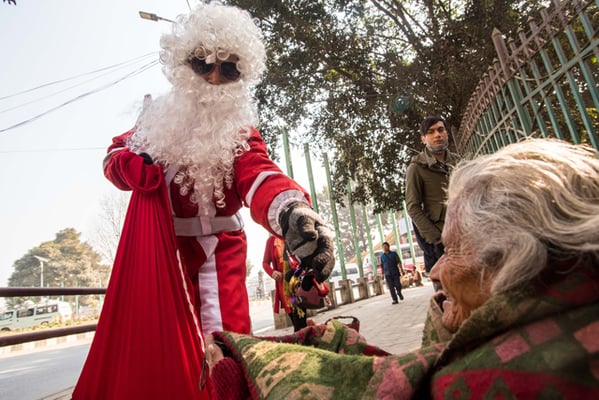 Salman Ghising, dressed as Santa Claus, gives out sweets on Christmas Day near Sundhara.