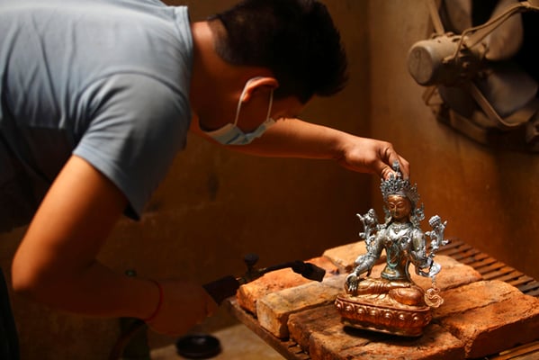 A worker in a metal handicraft workshop in Patan gives finishing touches to a statue of Green Tara on Monday.