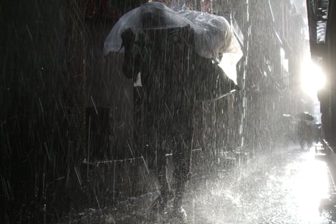 SUN AND RAIN: A porter carries goods on his back as he walks towards Bhotahiti on Monday.