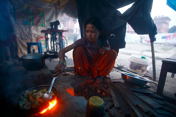 13-year-old Monika Tamang cooks food inside a temporary shelter in Chuchepati on Wednesday where her family moved after their house was destroyed in the April 25 earthquake. She has been using firewood to cook food due to the gas shortage caused by the ongoing Indian blockade.