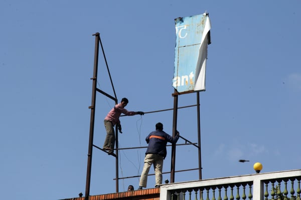 BALANCING ACT: Workers placing a hoarding board on the roof of Rastriya Banijya Bank at New Baneshwor.