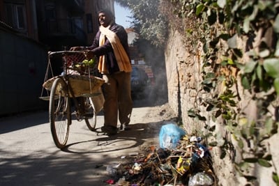 BONFIRE: A man passes near a pile of burning rubbish on the roadside in Kupondole on Monday. Kathmandu Metropolitan City (KMC) has introduced new measures to fine those who litter.