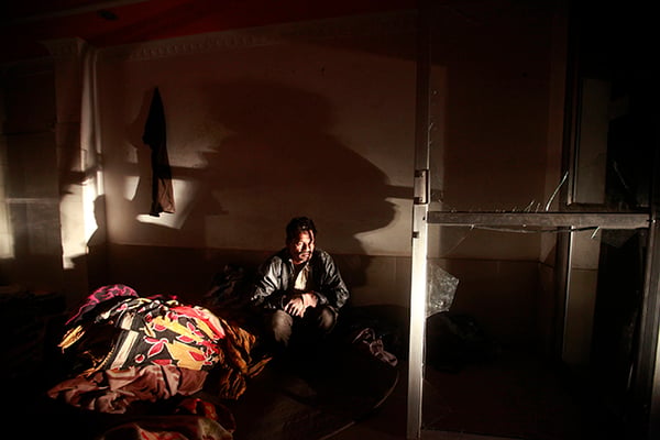 Migrant worker Akhtar Ali from India sits besides a broken glass door inside his house in Kathmandu on Monday. He was injured when he ran into the glass door in the aftermath of Friday's 5.5 magnitude earthquake