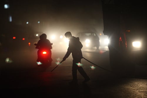 A worker cleans off the dust from the road near Kupondole on Tuesday.