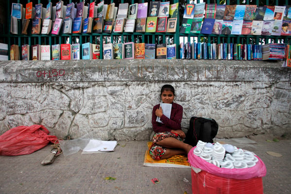 15 years old Sita Thapa reads a book while waiting for customers on Wednesday. Thapa sells CFL bulbs on the sidewalks of Sundhara.