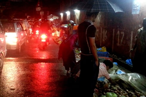 BUSINESS AS USUAL: Customers shop at the roadside vegetable market during the heavy downpour at Samakhusi on Sunday evening.