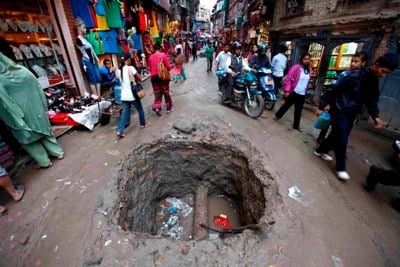 CRATER AHEAD: People pass by a water pipe under-construction at Ason on Thursday.