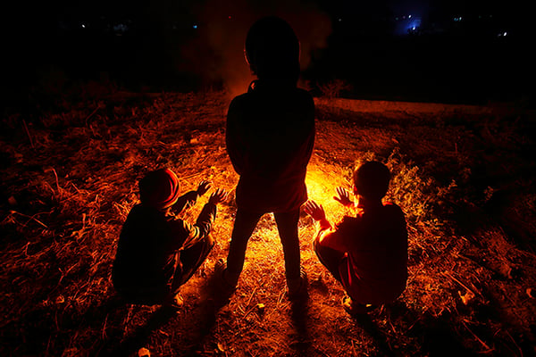 Children are silhouetted beside a bonfire near the Bagmati river on Thursday. Cold weather has peaked one month early this winter, as the minimum temperature falls to the low single digits in Kathmandu.