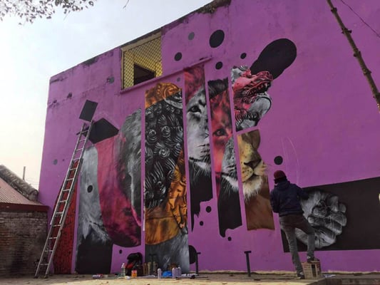 An artist paints an anthropomorphic artwork in Patan Dhoka on Friday. This wall painting is a part of Kathmandu Triennale, an international arts festival to be held in the capital next month.