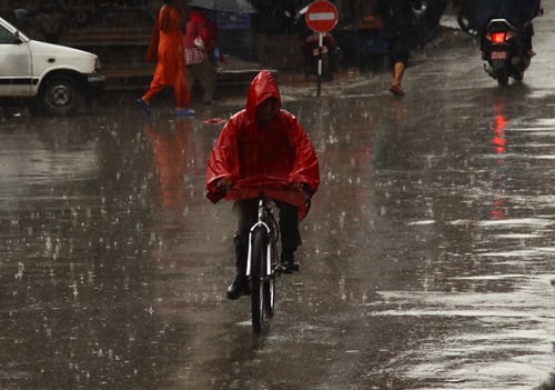 A man cycles through rain in Lalitpur on Monday evening.