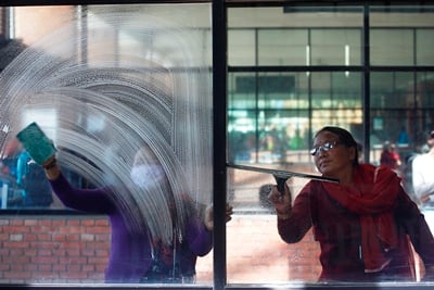 TWO SIDES OF THE STORY: Women clean windows at a waiting lounge of Tribhuvan International Airport on Friday.