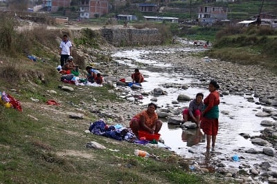 WASH YOUR CLOTHES IN PUBLIC: Women and children get together and wash clothes in the Nakhu river on Friday afternoon.