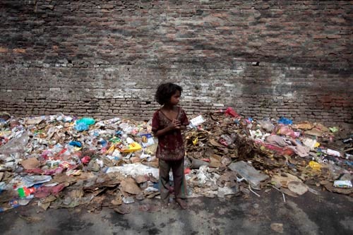A little girl stands in front of a pile of garbage at New Road on Monday. KMC has resumed garbage collection after four days of disruption.