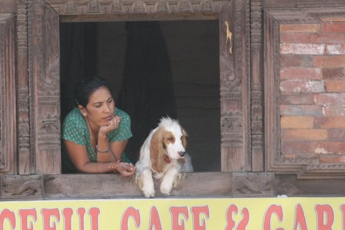 WINDOW SEAT: A woman and her dog look from their vantage point at Bhaktapur Darbar Square on Monday.
