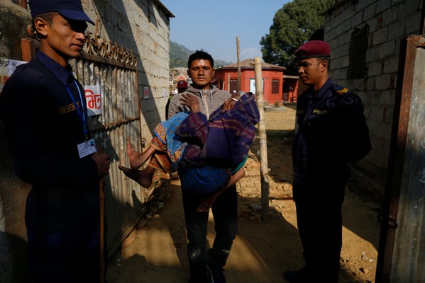 94-year-old Masuri Sakrini's son carries her out of the polling station after she cast her vote in Baglung on Sunday.