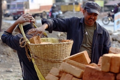 HEAVY LOAD: A man piles bricks to build his house with into a basket carried by his worker at Nakhu Dobato, Ring Road on Sunday.