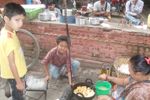 HELPING HANDS: School is out for Dasain, so 12-year-old Ashok Sahi (centre) helps his grandmother at their fried-snack stall in Itumbahal, on Monday near Kilagal.