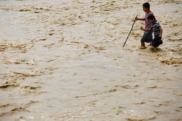 Boys try to cross an over-flooded street in Nakhu, Lalitpur. Encroachment into the floodplain of Nakhu River forced it to overflow into the adjoining streets on Sunday.